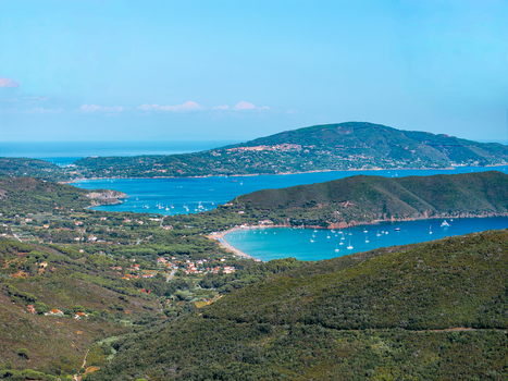 Aerial view of the coastal landscape near Passo del Monumento featuring turquoise waters boats in the bay and lush green hills in Campo nell Elba Toscana Italy.