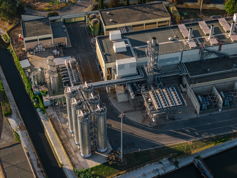Aerial view of an industrial plant featuring large metal silos complex piping systems and cooling units situated within a paved facility in Rome Lazio Italy.