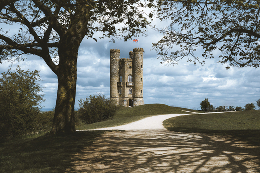 View of the picturesque Broadway Tower surrounded by serene trees and a tranquil path Middle Hill England.
