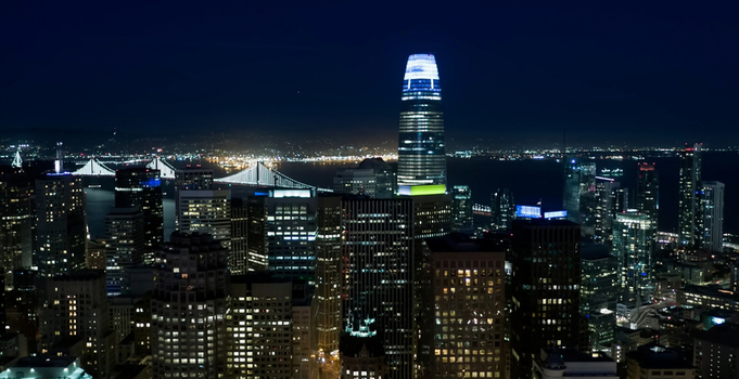 Aerial view of Salesforce Tower illuminated at night surrounded by the dense urban skyline of downtown San Francisco and the Bay Bridge San Francisco California United States. Aerial view of Salesforce Tower illuminated at night surrounded by the dense urban skyline of downtown San Francisco and the Bay Bridge San Francisco California United States.