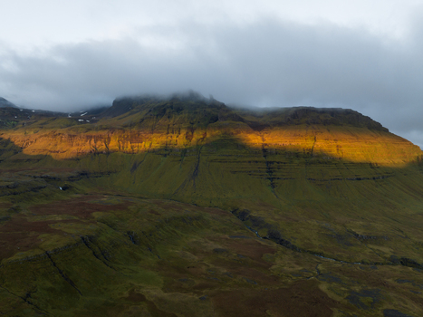 Aerial view of the mountain range bathed in golden sunlight contrasting with the deep greens and overcast skies Snæfellsnes Eyja og Miklaholtshreppur Iceland. Aerial view of the mountain range bathed in golden sunlight contrasting with the deep greens and overcast skies Snæfellsnes Eyja og Miklaholtshreppur Iceland.