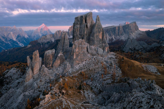 Aerial view of the Cinque Torri rock formations in the Dolomites featuring jagged peaks golden autumn larch trees and dramatic sunset light in Cortina d Ampezzo Veneto Italy.