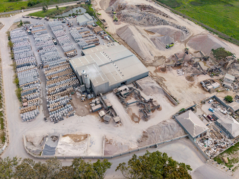 Aerial view of an industrial concrete and aggregate processing plant with large stockpiles of sand rows of stacked bricks and heavy machinery in Philippi Cape Town Western Cape South Africa.