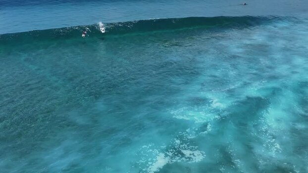 Aerial view of surfers riding a large turquoise wave Maldives. Aerial view of surfers riding a large turquoise wave Maldives.