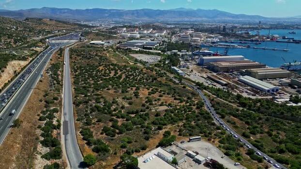 Aerial view of coastal highway and industrial port in Greece.