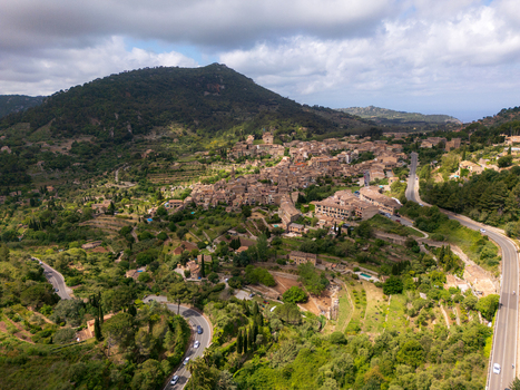 Aerial view of the historic town of Valldemossa nestled among lush green hills and winding mountain roads Valldemossa Balearic Islands Spain.