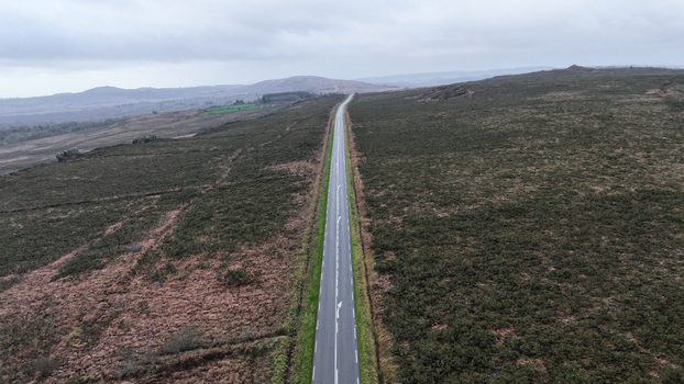 Aerial view of a straight road cutting through the moorland near Roc h Trevezel under an overcast sky in Plouneour Menez Brittany France.