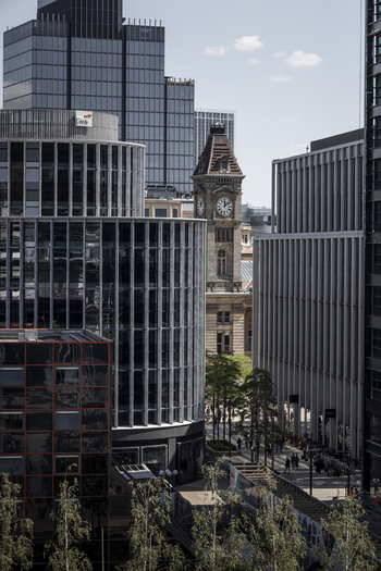 Aerial view of the historic Birmingham Council House clock tower framed by modern glass skyscrapers and urban architecture in Birmingham England United Kingdom.