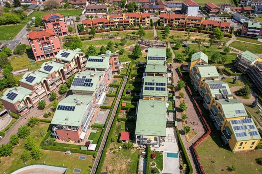 Aerial view of modern residential buildings featuring solar panels on green rooftops surrounded by lush gardens and pathways in Grugliasco Piedmont Italy. Aerial view of modern residential buildings featuring solar panels on green rooftops surrounded by lush gardens and pathways in Grugliasco Piedmont Italy.