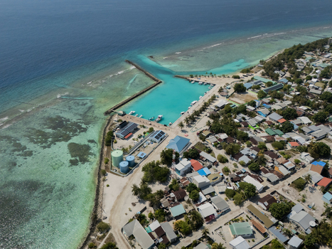 Aerial view of the tranquil harbor where azure waters meet the land a vibrant contrast to the clustered buildings Vashafaru Island Thiladhummathi Atoll Maldives.