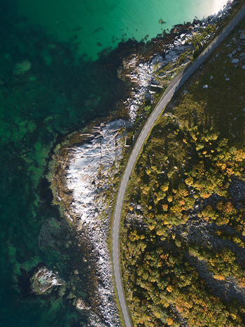 Aerial view of a winding coastal road along the turquoise waters and rocky shoreline of Vik Strand in Leknes Nordland Norway. Aerial view of a winding coastal road along the turquoise waters and rocky shoreline of Vik Strand in Leknes Nordland Norway.