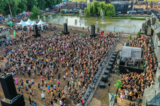 Herzogenaurach Germany 27 July 2025 Aerial view of Open Beatz Festival with a large crowd of people dancing near a stage and a pond with fountains. Herzogenaurach Germany 27 July 2025 Aerial view of Open Beatz Festival with a large crowd of people dancing near a stage and a pond with fountains.