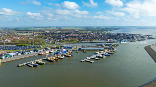 Aerial view of the harbor in Harlingen with fishing boats docked at piers historic town buildings in the background and the Wadden Sea in Harlingen Friesland Netherlands.