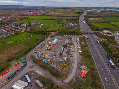Aerial view of a construction yard with heavy machinery and storage containers situated beside a highway near Doxey Marshes in Stafford England United Kingdom. Aerial view of a construction yard with heavy machinery and storage containers situated beside a highway near Doxey Marshes in Stafford England United Kingdom.