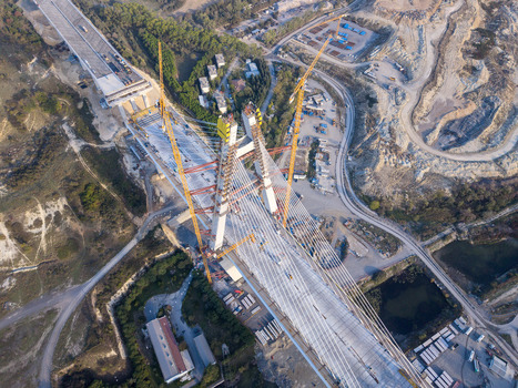 Aerial view of a large cable stayed bridge under construction with tall pylons steel cables and yellow cranes positioned over the road deck in a rural landscape Istanbul Istanbul Turkiye.