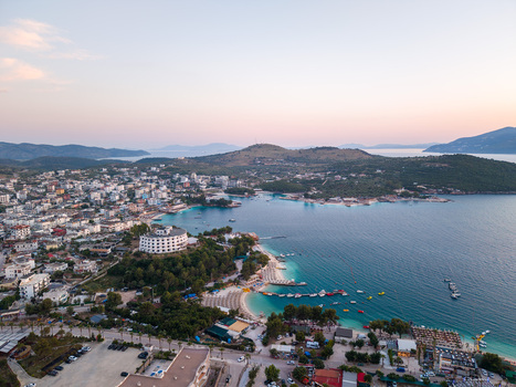 Aerial view of the coastal town featuring turquoise water sandy beaches and white buildings under a soft evening sky Ksamil Vlore County Albania. Aerial view of the coastal town featuring turquoise water sandy beaches and white buildings under a soft evening sky Ksamil Vlore County Albania.