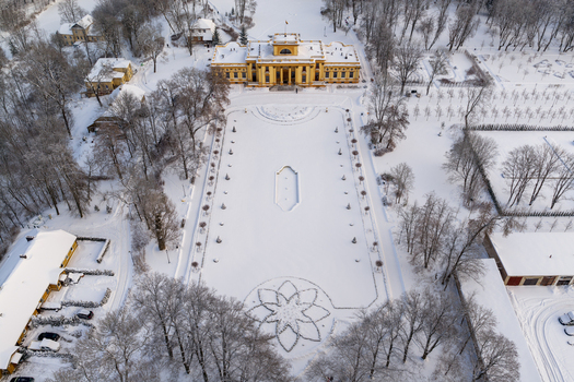 Aerial view of Traku Voke Manor a yellow neoclassical building featuring a snow covered courtyard with floral patterns and frosted trees in Vilnius Vilniaus apskritis Lithuania.