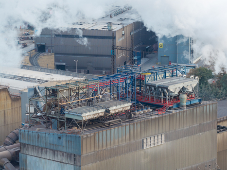 Aerial view of the Genk Zuid Rechteroever industrial facility featuring heavy steel manufacturing infrastructure complex piping and cooling units emitting steam in Genk Vlaanderen Belgium. Aerial view of the Genk Zuid Rechteroever industrial facility featuring heavy steel manufacturing infrastructure complex piping and cooling units emitting steam in Genk Vlaanderen Belgium.