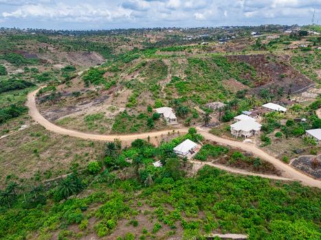Aerial view of winding dirt roads cutting through sparse vegetation and scattered buildings on hilly terrain Asaga Abia Nigeria. Aerial view of winding dirt roads cutting through sparse vegetation and scattered buildings on hilly terrain Asaga Abia Nigeria.