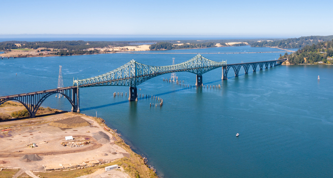 Aerial view of McCullough Memorial Bridge spanning the waters of Coos Bay with surrounding coastal landscape and clear blue sky in North Bend Oregon United States. Aerial view of McCullough Memorial Bridge spanning the waters of Coos Bay with surrounding coastal landscape and clear blue sky in North Bend Oregon United States.