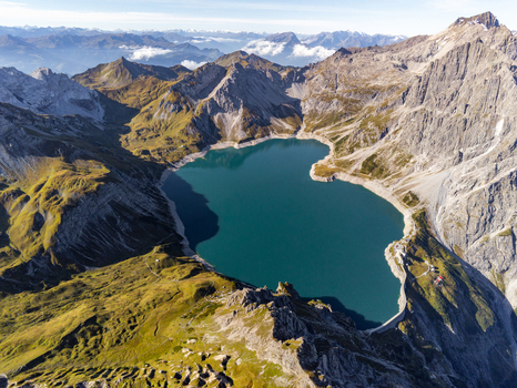 Aerial view of Lunersee surrounded by rugged alpine peaks steep mountain slopes and green meadows in Vandans Vorarlberg Austria. Aerial view of Lunersee surrounded by rugged alpine peaks steep mountain slopes and green meadows in Vandans Vorarlberg Austria.