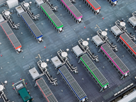 Aerial view of a data center roof featuring industrial cooling units complex piping systems and colorful ventilation structures in the United Kingdom.