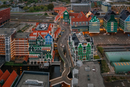 Zaandam Netherlands 26 April 2022 Aerial view of the Inntel Hotels Amsterdam Zaandam featuring its unique stacked house facade surrounded by modern buildings and a canal at dusk.