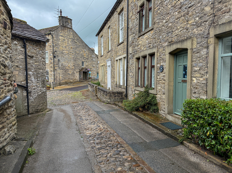 View of traditional Yorkshire stone cottages along a narrow cobblestone street under an overcast sky in Hawes England United Kingdom. View of traditional Yorkshire stone cottages along a narrow cobblestone street under an overcast sky in Hawes England United Kingdom.