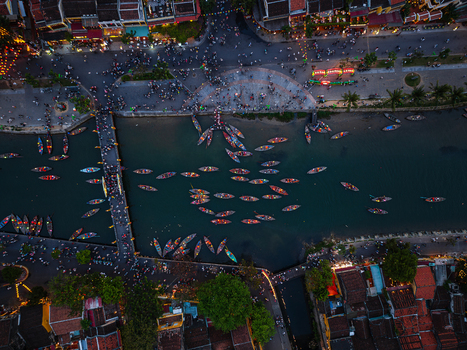 Aerial view of the Thu Bon River in Hoi An with numerous small wooden boats illuminated lanterns and historic architecture along the riverbanks in Vietnam. Aerial view of the Thu Bon River in Hoi An with numerous small wooden boats illuminated lanterns and historic architecture along the riverbanks in Vietnam.