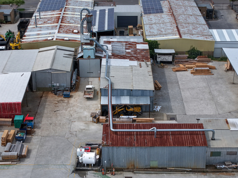 Melbourne VIC Australia 25 September 2026 Aerial view of an industrial factory site featuring metal roofed buildings stacks of timber heavy machinery and a prominent dust extraction system.