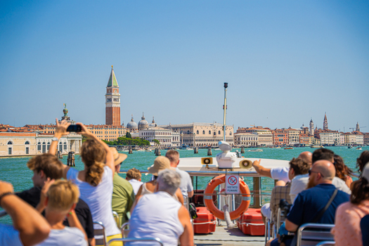 Venice Italy 29 March 2026 View of tourists gazing toward St. Mark s Campanile and the Doge s Palace under a vast cloudless sky with the serene water reflecting the city s warm hues. Venice Italy 29 March 2026 View of tourists gazing toward St. Mark s Campanile and the Doge s Palace under a vast cloudless sky with the serene water reflecting the city s warm hues.