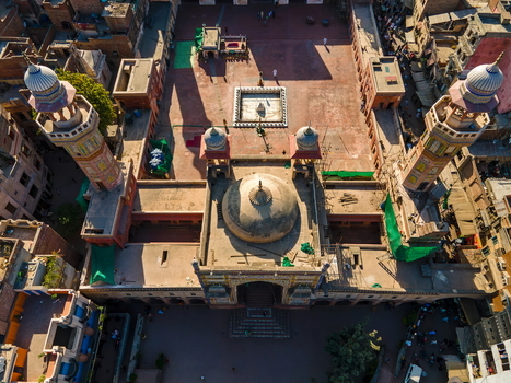 Aerial view of Wazir Khan Mosque featuring its iconic minarets central dome and historic courtyard surrounded by the dense urban fabric of Lahore Punjab Pakistan.