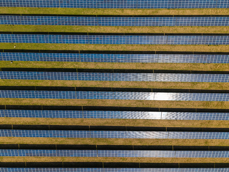 Aerial view of Lisburn Solar Farm with rows of photovoltaic panels arranged in parallel lines across green grass fields in Lisburn Northern Ireland United Kingdom. Aerial view of Lisburn Solar Farm with rows of photovoltaic panels arranged in parallel lines across green grass fields in Lisburn Northern Ireland United Kingdom.