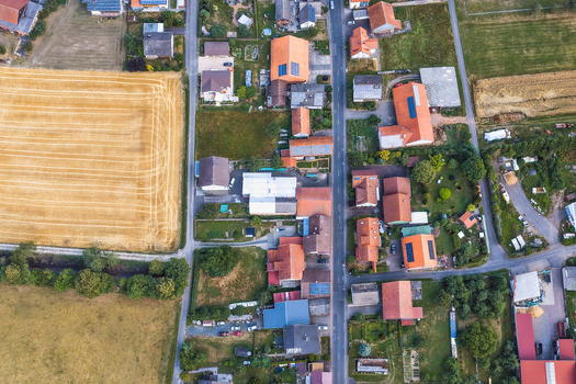 Aerial view of the town with its characteristic red tiled roofs residential houses solar panels and surrounding agricultural fields in the rural landscape of Burghaun Hessen Germany. Aerial view of the town with its characteristic red tiled roofs residential houses solar panels and surrounding agricultural fields in the rural landscape of Burghaun Hessen Germany.