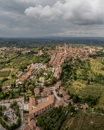 Aerial view of the historic medieval town of San Gimignano with its iconic towers surrounded by lush rolling hills vineyards and olive groves in San Gimignano Tuscany Italy. Aerial view of the historic medieval town of San Gimignano with its iconic towers surrounded by lush rolling hills vineyards and olive groves in San Gimignano Tuscany Italy.