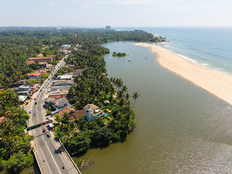 Aerial view of a tropical coastal landscape featuring a river lagoon sandy beach and lush palm trees along the shoreline in Galle Southern Province Sri Lanka.