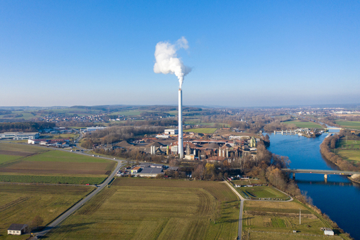 Aerial view of the Liapor GmbH Co. KG industrial plant with a tall smoking chimney and surrounding fields by the river in Hallerndorf Bayern Germany. Aerial view of the Liapor GmbH Co. KG industrial plant with a tall smoking chimney and surrounding fields by the river in Hallerndorf Bayern Germany.
