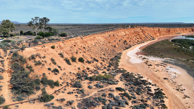Aerial view of the red cliffs at Matthew Flinders Red Cliff Lookout featuring rugged orange earth sparse vegetation and a tidal inlet in Port Augusta West South Australia Australia. Aerial view of the red cliffs at Matthew Flinders Red Cliff Lookout featuring rugged orange earth sparse vegetation and a tidal inlet in Port Augusta West South Australia Australia.