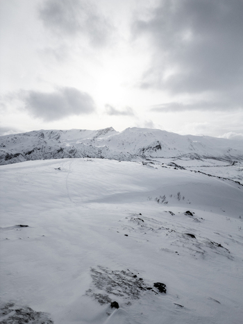 Aerial view of snow covered mountain peaks and vast white slopes under a cloudy winter sky in Ersfjord Troms Norway. Aerial view of snow covered mountain peaks and vast white slopes under a cloudy winter sky in Ersfjord Troms Norway.