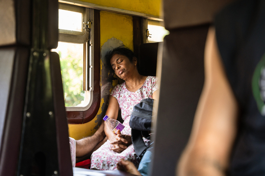 Sri Lanka 06 February 2026 View of a woman sleeping on a train carriage seat next to a window while holding a water bottle.