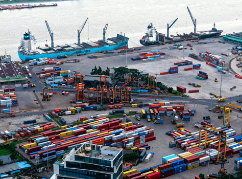 Aerial view of Chattogram Port with large container ships docked numerous colorful shipping containers stacked in the yard and industrial cranes in Chittagong Chittagong Division Bangladesh.
