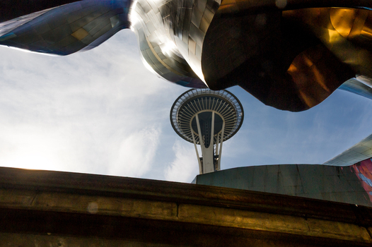 View of the Space Needle framed by the metallic curved architecture of the Museum of Pop Culture in Seattle Washington United States.