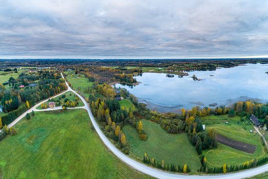 Aerial view of the landscape surrounding Cesis with a winding road a calm lake and autumn colored trees under a cloudy sky in Cesis Cesis Municipality Latvia. Aerial view of the landscape surrounding Cesis with a winding road a calm lake and autumn colored trees under a cloudy sky in Cesis Cesis Municipality Latvia.