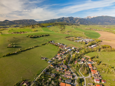 Aerial view of the village of Liptovsky Trnovec with houses nestled among green fields and rolling hills under a blue sky Liptovsky Trnovec Zilina Region Slovakia.