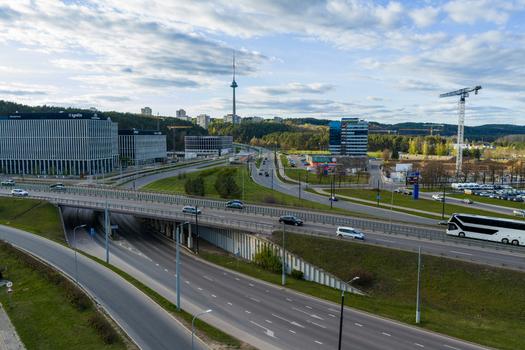 Vilnius Lithuania 01 May 2026 Aerial view of the Vilnius TV Tower rising above modern office buildings a highway overpass with traffic and lush green hills under a cloudy sky. Vilnius Lithuania 01 May 2026 Aerial view of the Vilnius TV Tower rising above modern office buildings a highway overpass with traffic and lush green hills under a cloudy sky.