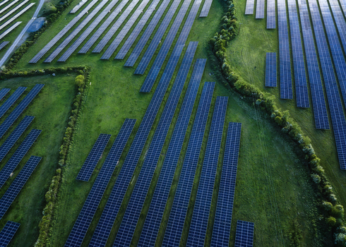 Aerial view of Gillinstown Solar Farm with rows of photovoltaic panels set among lush green fields and hedgerows County Meath Ireland.