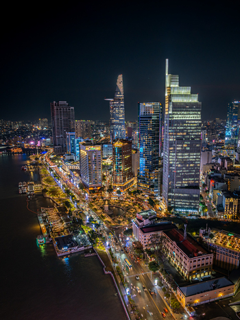 Aerial view of the illuminated Ho Chi Minh City skyline at night featuring the Bitexco Financial Tower modern skyscrapers and the Saigon River Ho Chi Minh City Vietnam. Aerial view of the illuminated Ho Chi Minh City skyline at night featuring the Bitexco Financial Tower modern skyscrapers and the Saigon River Ho Chi Minh City Vietnam.