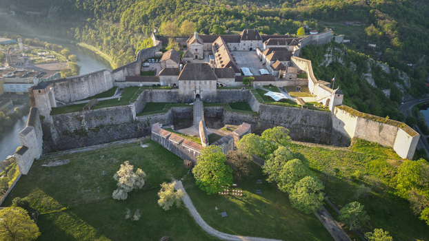 Aerial view of the Besancon Citadel with its massive stone fortifications and historic buildings overlooking the Doubs river and lush green hills in Besancon Bourgogne Franche Comte France. Aerial view of the Besancon Citadel with its massive stone fortifications and historic buildings overlooking the Doubs river and lush green hills in Besancon Bourgogne Franche Comte France.