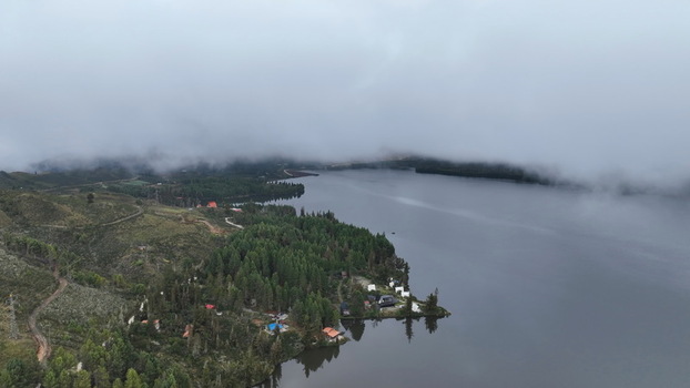Aerial view of Corani Lake surrounded by dense pine forests and rolling hills under a cloudy sky in Chapare Cochabamba Department Bolivia.