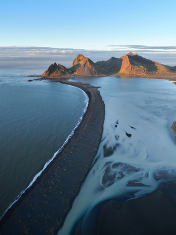 Aerial view of the stark black sand beach meeting the glacial waters under the gaze of the majestic Vestrahorn mountain range Höfn Iceland. Aerial view of the stark black sand beach meeting the glacial waters under the gaze of the majestic Vestrahorn mountain range Höfn Iceland.